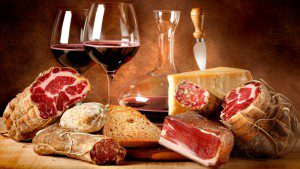 A table with wine, bread and meat on it.