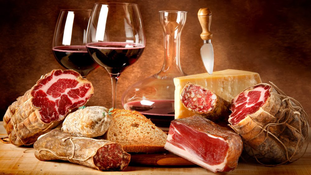 A table with wine, bread and meat on it.