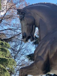 A horse statue in front of trees and sky.